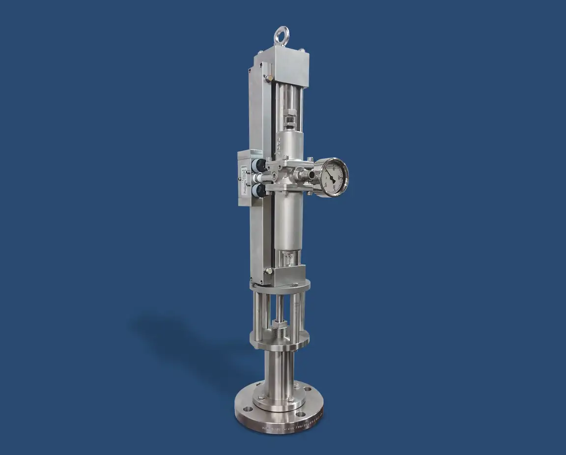 Image of a vertical industrial machine component with metallic parts and a pressure gauge attached, set against a blue background. The top-head drive pump appears to be a fluid or gas control mechanism, featuring cylindrical shapes and a sturdy base.