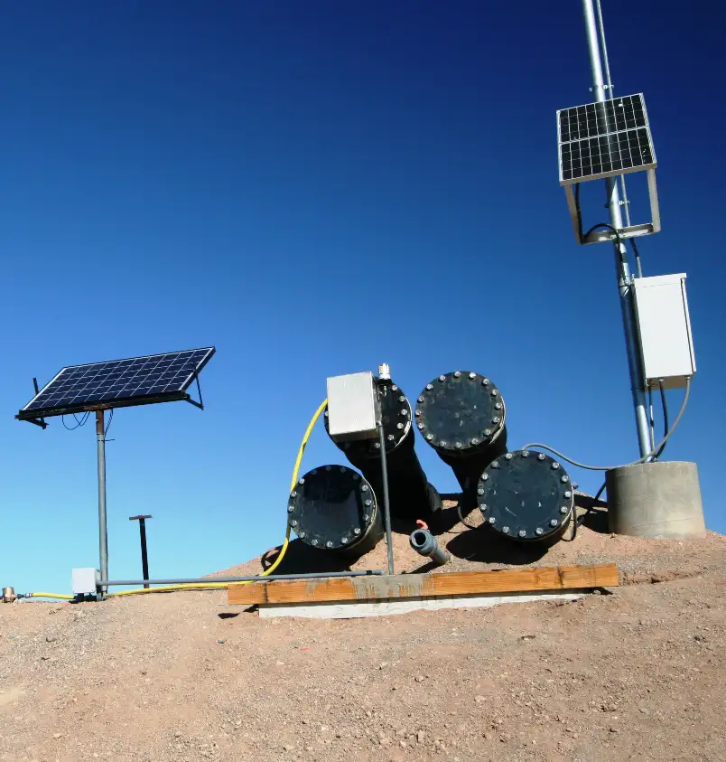 Solar panel on a pole beside a cluster of large horizontal pumps.